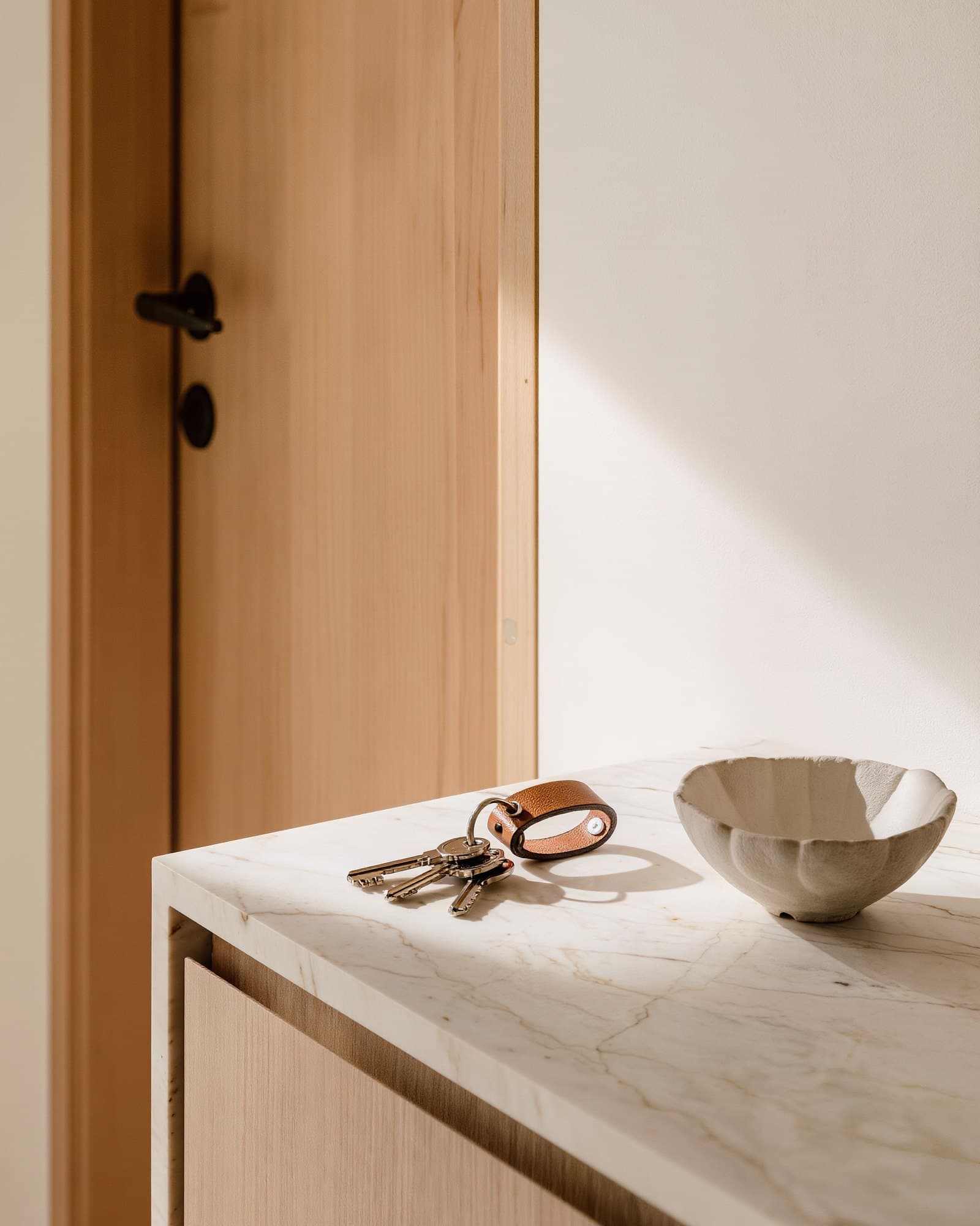 Keys on a leather key ring on a marble console in the entrance